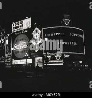 Anni sessanta, foto storiche che mostra il famoso neon di cartelli pubblicitari e slogan illuminare la notte al Piccadilly Circus rotatoria nel west end di Londra, Inghilterra, Regno Unito. Foto Stock