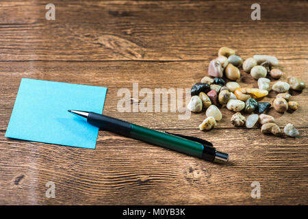 Matita poste sui post-it con molti ciottoli in background in legno Foto Stock