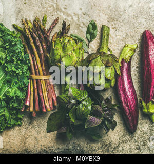 Flat-lay di verde e viola la verdura fresca su sfondo concreto, vista dall'alto, quadrato raccolto. Produzione locale per cucina salutare. Eggplans, fagiolo verde Foto Stock