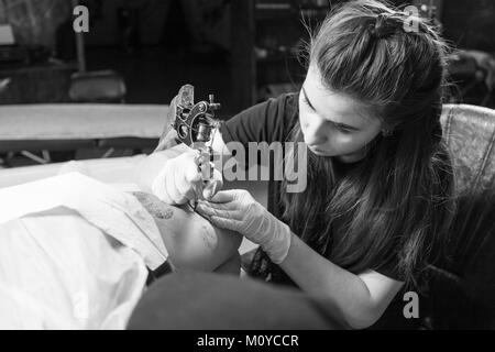 Bella dai capelli scuri tatuaggio donna artista il disegno di un tatuaggio per un tatuaggio, close-up, vista dal basso Foto Stock