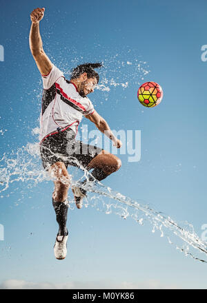 La spruzzatura di acqua su uomo ispanico voce pallone da calcio Foto Stock