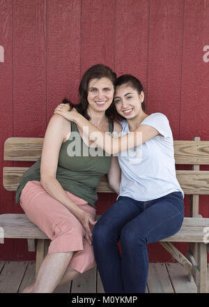 Ritratto di sorridente ragazza caucasica abbracciando la madre sul banco di lavoro Foto Stock