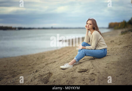 Malinconici donna seduta sulla spiaggia Foto Stock