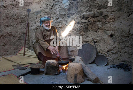 Nizwa, Oman, Dicembre 15th, 2016: Omani uomo torrefazione di caffè arabo in una casa tradizionale Foto Stock