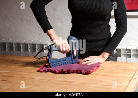 Il processo per la fabbricazione di una donna di pelliccia. Un close-up di una giovane donna pellicciaio si asciuga e si distende la pelle di una speciale macchina con pelliccia naturale per mak Foto Stock