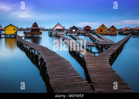 Bokod lago, Ungheria - il famoso villaggio galleggiante con pontili e pesca tradizionale cottage in legno su un nuvoloso al mattino invernale Foto Stock