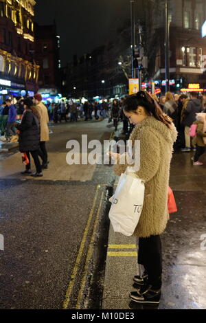 Donna orientale utilizzando il proprio smartphone su carbonizzazione Cross Road, Londra, Inghilterra, Regno Unito Foto Stock