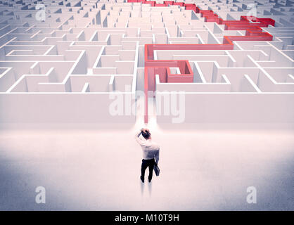 Un imprenditore nel soddisfare dando pollice in alto nella parte anteriore del labirinto con la linea rossa mostra la via di uscita Foto Stock