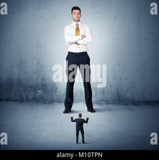 Arrabbiato enorme business man lokking al piccolo ragazzo collega concetto sullo sfondo Foto Stock