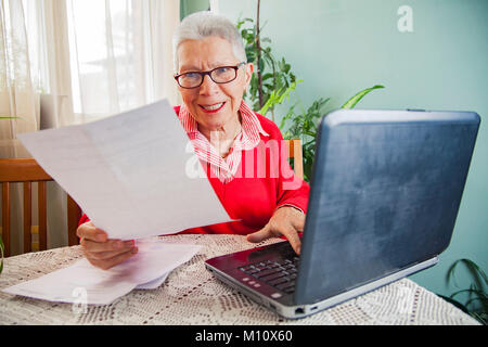 Senior donna oltraggiate con fatture di società di elettricità Foto Stock