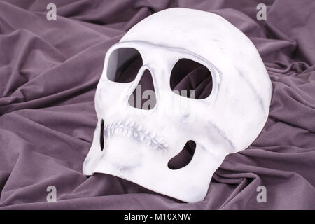 Cranio bianco maschera sullo sfondo del tessuto. Foto Stock