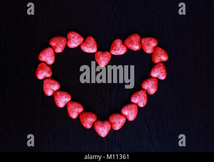 Cuore rosso fatta di piccoli cuori su sfondo scuro closeup. Foto Stock