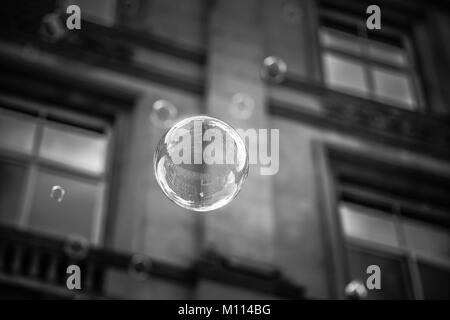 Un bianco e nero closeup immagine di una bolla galleggiante attraverso una strada a Glasgow, Scozia Foto Stock