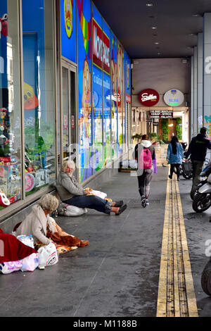 Strada Commerciale di Ermou con traversine ruvida lungo il marciapiede e gli acquirenti passando, Atene, Grecia Foto Stock