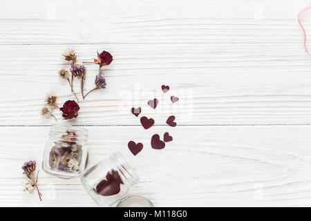 Elegante cuori nel vasetto di vetro e Roses Appartamento giaceva sul bianco sullo sfondo di legno. felice il giorno di San Valentino. singolare biglietto di auguri con spazio per testo o per matrimoni Foto Stock
