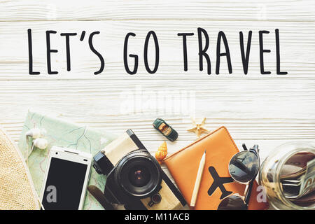 Viaggio. Let's go travel testo concetto di segno, wanderlust vacanza sfondo laici piana. telecamera occhiali da sole passaporto denaro telefono mappa hat piano auto su bianco Foto Stock