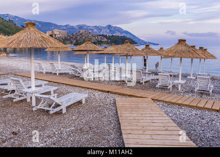 Vuoto spiaggia slava nella città di Budva sul Mare Adriatico costa in Montenegro. Giardini Dukley complesso residenziale sullo sfondo Foto Stock