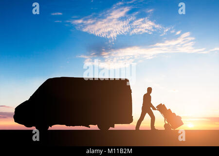 Silhouette di corriere per la consegna con scatole di cartone su carrello in prossimità del Van al tramonto Foto Stock