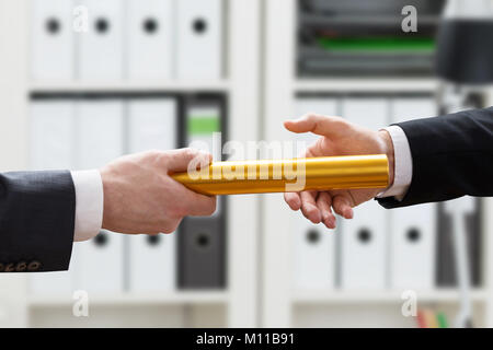 Close-up di imprenditore il passaggio di mano del relè d'oro il testimone al suo collega in ufficio Foto Stock