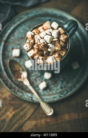 Riscaldamento invernale dolce bere cioccolata calda con marshmallows e cacao in tazza su sfondo di legno, fuoco selettivo Foto Stock