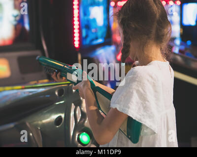 Bambina la riproduzione di gioco sparatutto in theme park. Foto Stock