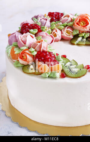 Festosa torta con crema di fiori e di frutti su uno sfondo luminoso Foto Stock