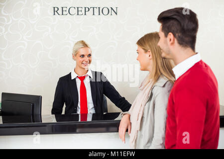 Coppia giovane il check-in presso la reception dell'hotel Foto Stock