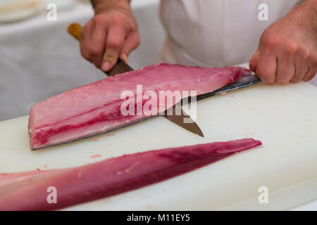 Chef giapponese e taglio per affettare il pesce fresco per rendere il sashimi e sushi per diners Foto Stock