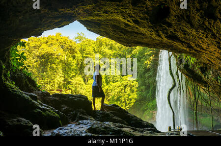 Turista nella grotta guardando a Misol Ha una cascata nei pressi di Palenque in Chiapas, Messico Foto Stock