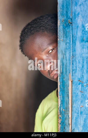 Bambino africano in piedi dietro una porta nel villaggio, Botswana Foto Stock