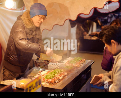 Giapponese street food venditore a vendere Hashimaki, Okonomiyaki laminati sulle bacchette, presso una strada mercato alimentare a Kyoto, Giappone Foto Stock