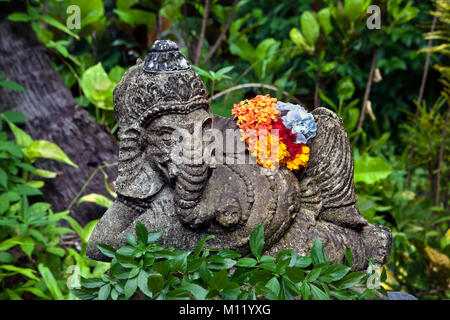Indonesia, isola di Bali, vicino al villaggio di Tejakula, Gaia Oasis Resort. Statua del dio indù Ganesha con fiore in giardino. Foto Stock