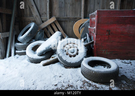 Pila di vecchi pneumatici per auto coperto di neve nel vecchio garage in legno Foto Stock