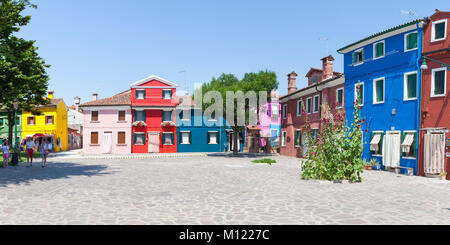 Panorama di case vivacemente colorate di Burano Venezia Italia intorno a una piazza tranquilla, Corte della Comare, con un paio di passeggiate attraverso in una giornata di sole Foto Stock