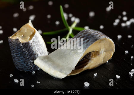In prossimità dei due pezzi di aringhe marinate il pesce con sale sull'ardesia Foto Stock