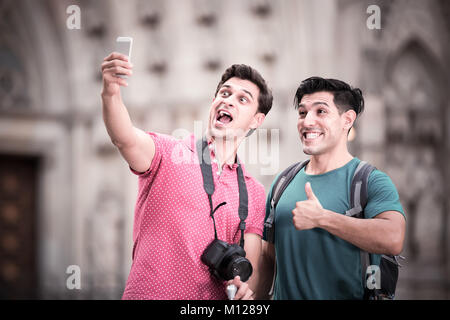 Uomini positivo per i turisti con le valigie sono rendendo selfie su di una strada nella città sconosciuta. Foto Stock