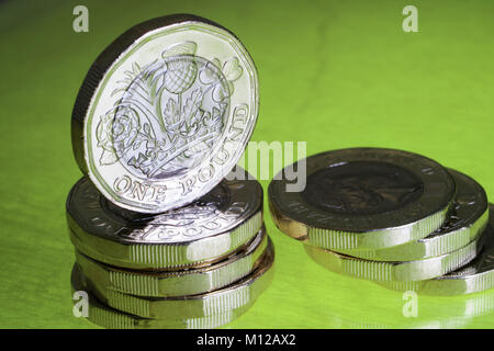 Nuovo cancelletto monete disposti su un verde illuminato base con una moneta evidenziata in posizione verticale Foto Stock