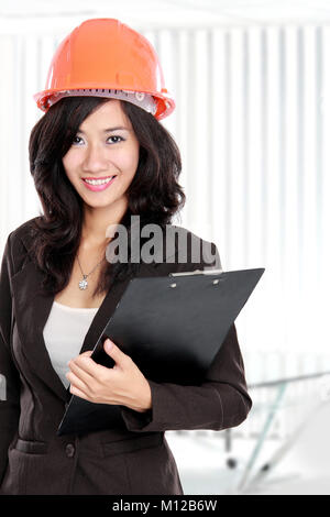 Fiducioso giovane donna indossa orange hardhat casco Foto Stock