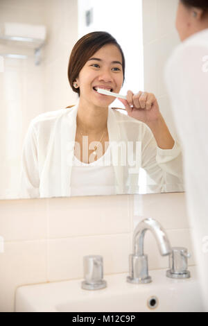 Un ritratto di un asiatico giovane donna di spazzolatura dei denti denti lei felicemente Foto Stock