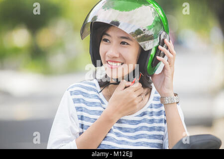 Donna felice il fissaggio il suo casco in moto nella strada di città Foto Stock