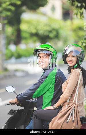 Commerciale felice motociclo taxi driver prendendo il suo passeggero per la sua destinazione Foto Stock