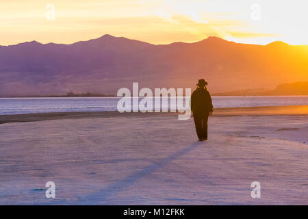 Donna che cammina verso il tramonto sul Bonneville Saline, che è BLM land ad ovest del Grande Salt Lake, Utah, Stati Uniti d'America Foto Stock