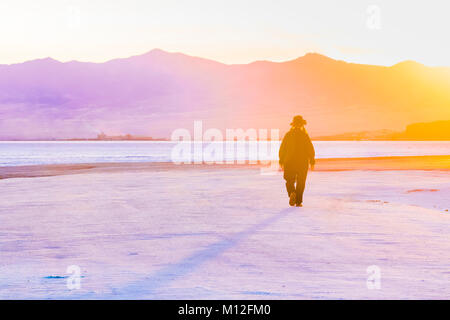 Donna che cammina verso il tramonto sul Bonneville Saline, che è BLM land ad ovest del Grande Salt Lake, Utah, Stati Uniti d'America Foto Stock