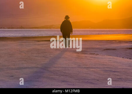 Donna che cammina verso il tramonto sul Bonneville Saline, che è BLM land ad ovest del Grande Salt Lake, Utah, Stati Uniti d'America Foto Stock