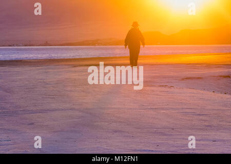 Donna che cammina verso il tramonto sul Bonneville Saline, che è BLM land ad ovest del Grande Salt Lake, Utah, Stati Uniti d'America Foto Stock