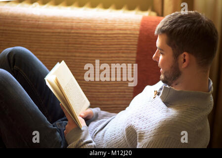 Giovane uomo che gode di un grande libro Foto Stock