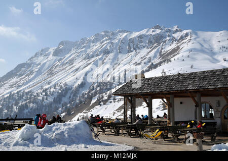 ARABBA, Italia - 7 Marzo 2011: gli sciatori e gli snowboarder gustando un caffè e prendere il sole outdoor presso un ristorante italiano a montagne dolomitiche Foto Stock