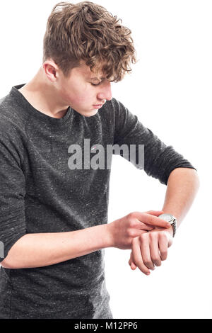 Un ragazzo di quattordici anni guardando il suo orologio in studio Foto Stock