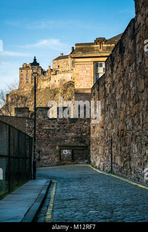 Parete Flodden e Vennel alley con il Castello di Edimburgo sperone roccioso illuminato da Sun in background, Edimburgo, Scozia, Regno Unito Foto Stock