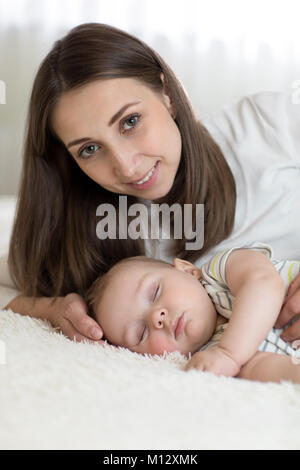 Ritratto di Madre bella con i suoi 7 mesi di età bambino dorme nel letto Foto Stock